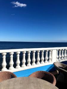 Hotel Ariana في Marine du Miomo: شرفة مع طاولة وكراسي تطل على المحيط