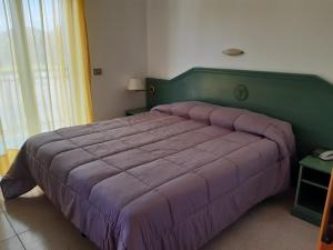ジャルディーニ・ナクソスにあるVillaggio Alkantaraのベッドルーム1室(大型ベッド1台、紫色の掛け布団付)