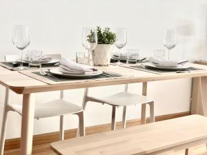 una mesa de madera con vasos, platos y sillas en Apartamento La Sal en León
