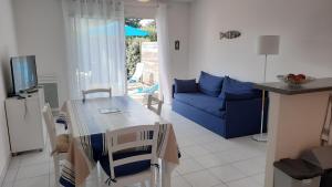 a living room with a table and a blue couch at PAREE D EAU 104 - Résidence avec piscine - Appartement rez de jardin 1 chambre in Notre-Dame-de-Monts