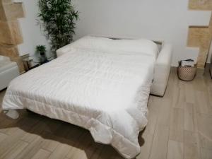 ein weißes Bett in einem Schlafzimmer mit Holzboden in der Unterkunft Casa al Teatro in Syrakus