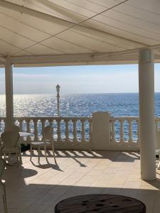 Hotel Ariana في Marine du Miomo: شرفة مع طاولة وكراسي والمحيط