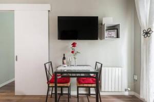 a dining room table with chairs and a television on a wall at Camp Nou , Fira Barcelona Apartment in Hospitalet de Llobregat