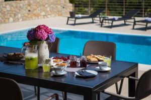 una mesa negra con desayuno y bebidas junto a la piscina en Villa Madrevita Exclusive, en Zaton