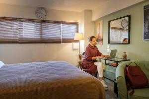a woman sitting in a hotel room with a laptop at Pol's studio, Kalamata Mediterranean Apartments in Kalamata +33 photos