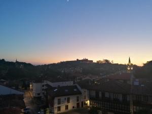 uma cidade ao pôr-do-sol com um castelo numa colina em Pension Villa ** em Comillas