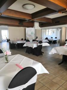 a banquet hall with white tables and black chairs at Zur Linde in Mainzweiler