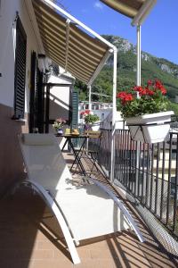 Biały fotel na balkonie ze stołem i kwiatami w obiekcie Casa Nanà Amalfi Coast w mieście Vietri sul Mare