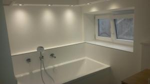eine weiße Badewanne in einem Badezimmer mit Fenster in der Unterkunft Ferienhaus Chiemsee in Übersee + 23 Fotos