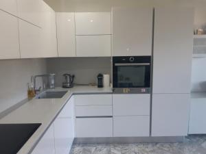 a white kitchen with white cabinets and a microwave at Résidence climatisée, belle vue, 5min de la plage. in Roquebrune-Cap-Martin