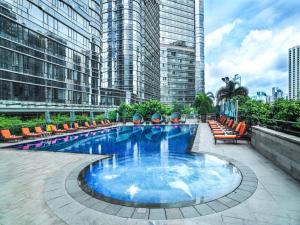 a large swimming pool with chairs and buildings at Fraser Suites Guangzhou in Guangzhou
