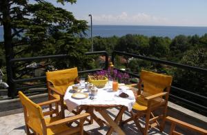 een tafel en stoelen op een balkon met uitzicht op de oceaan bij Orfeas -Vacation Home in Paralia Panteleimonos