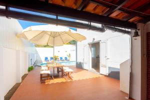 un patio avec une table et un parasol dans l'établissement Villa Sol e Mar, à Charneca