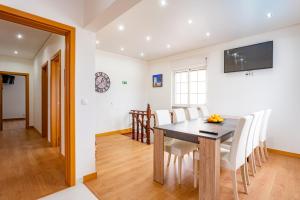 une salle à manger avec une table et des chaises blanches dans l'établissement Villa Sol e Mar, à Charneca