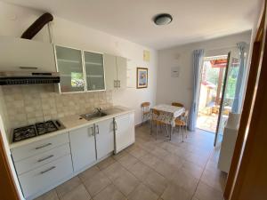 uma cozinha com armários brancos, um lavatório e uma mesa em Apartments Matlovac em Zdrelac