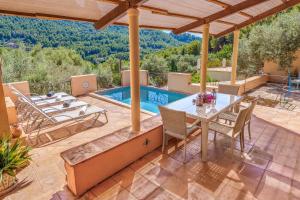a patio with a table and chairs and a swimming pool at Ca n'aina in Cala Tuent