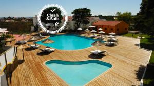 a view of a pool with chairs and umbrellas at Hotel Vale Da Telha in Aljezur
