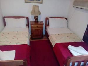 two beds in a room with a table and a lamp at Pansion Mimoza in Herceg-Novi