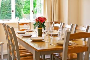 a wooden table with glasses and a vase with red roses at Northlands Farm - Old Farm Cottage in Chichester