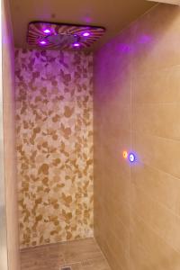 baño con ducha con luces moradas en la pared en B&B Fabiola, en Pompeya