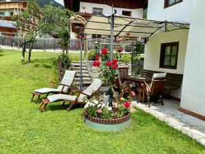 um pátio com uma mesa, cadeiras e um guarda-sol em Dolomites Charme Chalet em Colle Santa Lucia