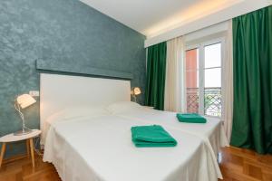 a bedroom with a white bed with green curtains and a window at Villa Oria in Pula +26 photos