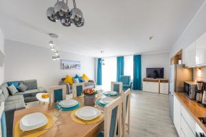 a kitchen and a living room with a dining room table at Apartamenty Sun & Snow Olymp in Kołobrzeg