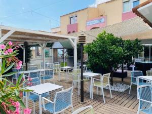 a patio with tables and chairs on a deck at Hotel & Spa Gil de France Cap d'Agde in Cap d'Agde