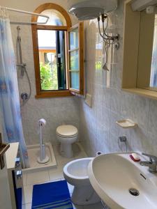 ein Bad mit einem Waschbecken, einem WC und einem Fenster in der Unterkunft Villaggio Teodorico in Punta Marina