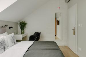 a bedroom with a large bed and a black chair at Villa Antiqua in Racibórz