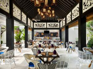 Avani Seminyak Bali Resort في سمينياك: مطعم بطاولات وكراسي وبار