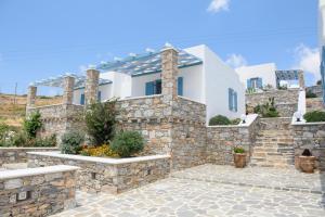 ein weißes Haus mit einer Steinmauer in der Unterkunft Οasis Apartments in Amorgós