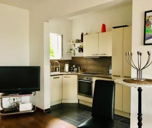 a kitchen with white cabinets and a table with a television at Großes, helles Apartement - Nähe Marburg & Gießen in Fronhausen