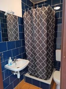 トルンにあるGościniec Silverの青いタイル張りのバスルーム(シンク、シャワーカーテン付)