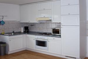 a white kitchen with white cabinets and a refrigerator at Appartement Georg in Celle +1 photo