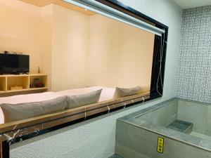 a large mirror in a room with a bed and a tub at 日月潭沅居民宿 YUAN JU BOUTIQUE Hotel in Yuchi