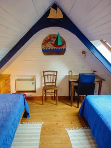 a room with two beds and a table and a chair at Maison de la Ferme in Lézardrieux