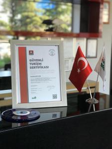 ein Schild auf einem Tisch mit einer Flagge und einer Uhr in der Unterkunft Baliktasi City Hotel & Spa in Altınordu