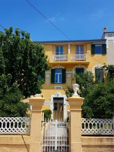 a yellow house with a white fence in front of it at Apartments Eis in Baška