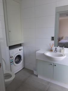 a white bathroom with a washing machine and a sink at City Apartment in Christchurch