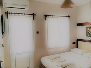 a bedroom with two beds and two windows at Ladies Beach Hotel in Kuşadası