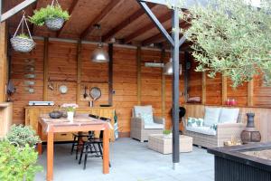 a patio with a table and chairs and a wooden wall at B & B Janneke Elsloo Friesland in Elsloo