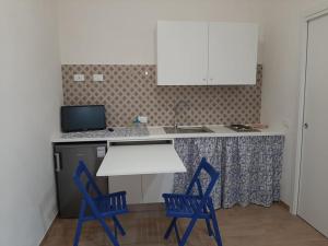 una cucina con due sedie blu e un tavolo bianco di LA NICCHIA a Marsala
