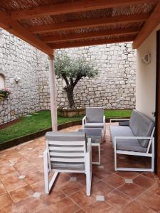 eine Terrasse mit 2 Stühlen, einem Sofa und einem Baum in der Unterkunft Appartamento DELUXE 1 con vasca idromassaggio vista Lago di Garda, riscaldata, privata e utilizzabile tutto l'anno in Brenzone sul Garda