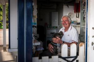 an older man holding a dog in a room at Hotel Perla in Castiglione della Pescaia