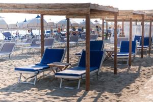 a group of chairs and tables on a beach at Hotel Perla in Castiglione della Pescaia