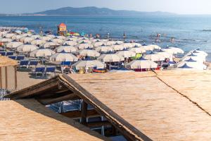 a beach with many umbrellas and people on the water at Hotel Perla in Castiglione della Pescaia