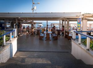 people sitting at tables on the deck of a restaurant at Hotel Perla in Castiglione della Pescaia