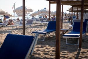 a group of chairs and umbrellas on a beach at Hotel Perla in Castiglione della Pescaia