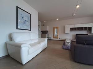 a living room with a white couch and a chair at BMP APARTMENT DELUXE 2 JACUZZI RISCALDATA PRIVATA vista Lago di Garda in Brenzone sul Garda